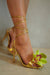 Gold high-heeled sandals with a green orchid embellishment